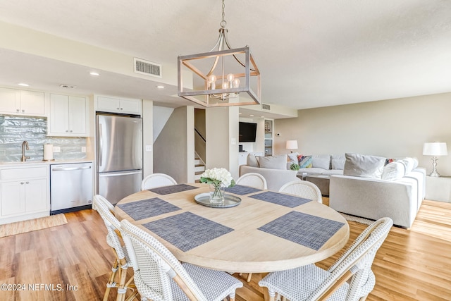 dining room with a notable chandelier, recessed lighting, visible vents, light wood-style flooring, and stairs