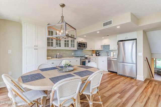 dining space with recessed lighting, visible vents, an inviting chandelier, light wood-type flooring, and baseboards