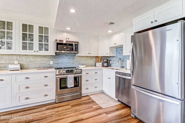 kitchen with a sink, visible vents, light countertops, appliances with stainless steel finishes, and light wood finished floors