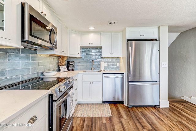 kitchen with appliances with stainless steel finishes, visible vents, a sink, and wood finished floors