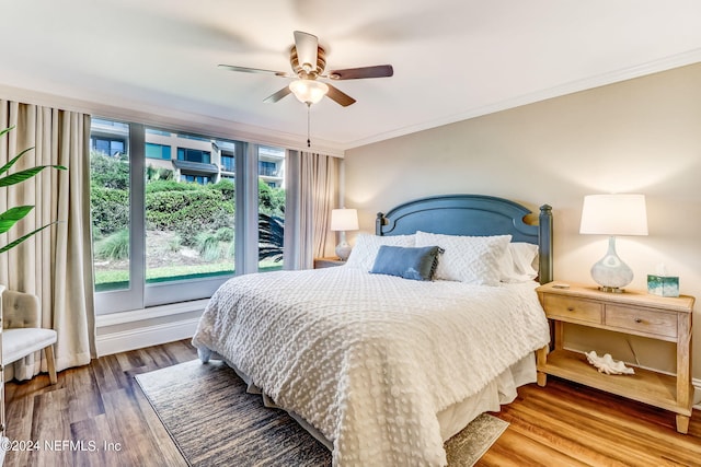 bedroom with ceiling fan, wood finished floors, and crown molding