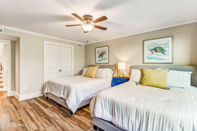 bedroom with light wood-type flooring, ornamental molding, and a closet