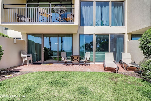 back of property featuring a yard, a patio area, a balcony, and stucco siding