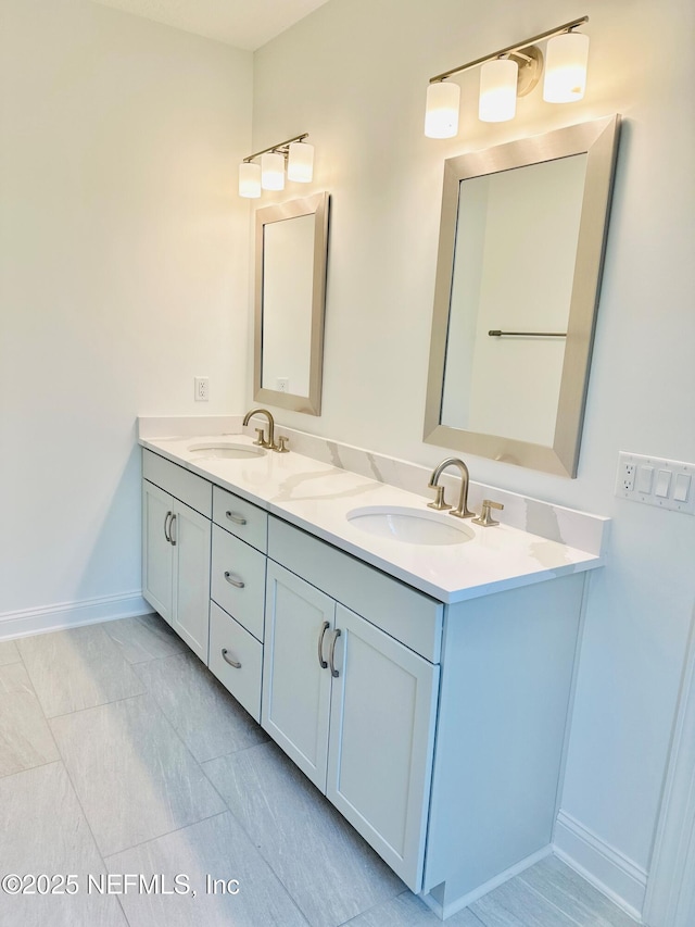 bathroom with double vanity, baseboards, and a sink