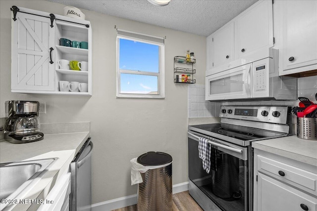 kitchen with tasteful backsplash, white cabinetry, wood-type flooring, stainless steel appliances, and a textured ceiling