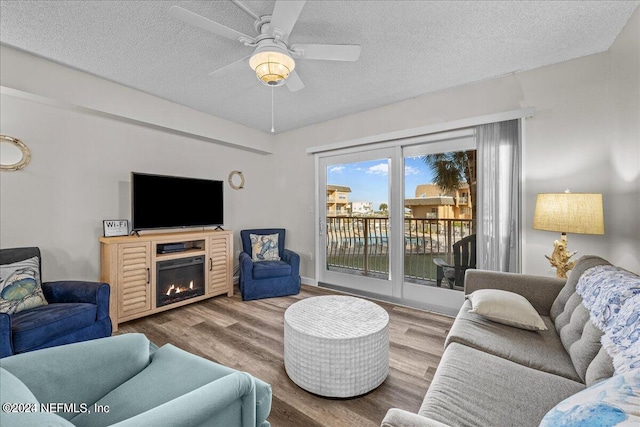 living room with ceiling fan, wood-type flooring, and a textured ceiling