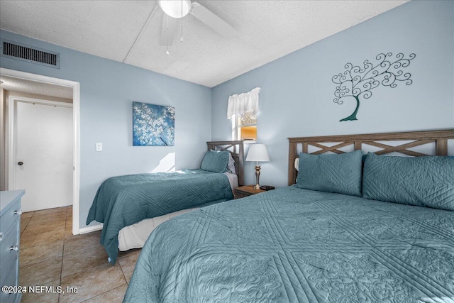 tiled bedroom with ceiling fan and a textured ceiling