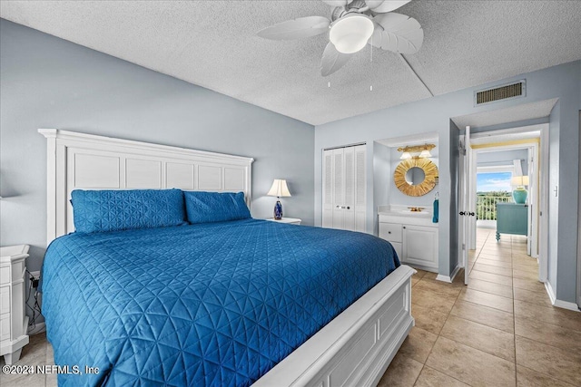 bedroom with ceiling fan, light tile patterned floors, a closet, and a textured ceiling