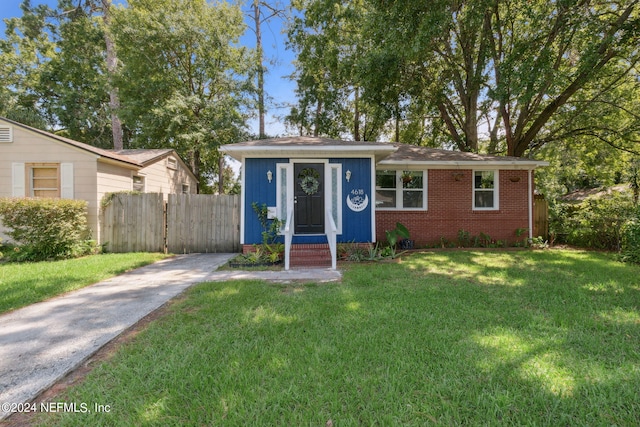 view of front facade with brick siding, a front yard, and fence