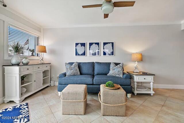 living area featuring ceiling fan, light tile patterned floors, and baseboards