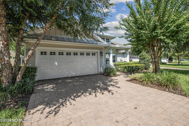 view of front facade with decorative driveway, a standing seam roof, metal roof, and an attached garage