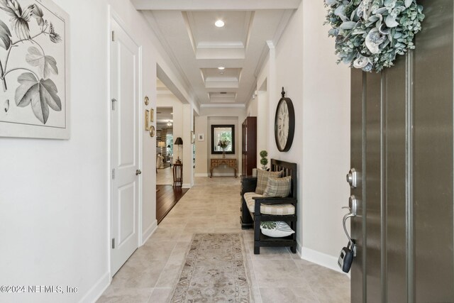 corridor with ornamental molding, light hardwood / wood-style flooring, and a tray ceiling