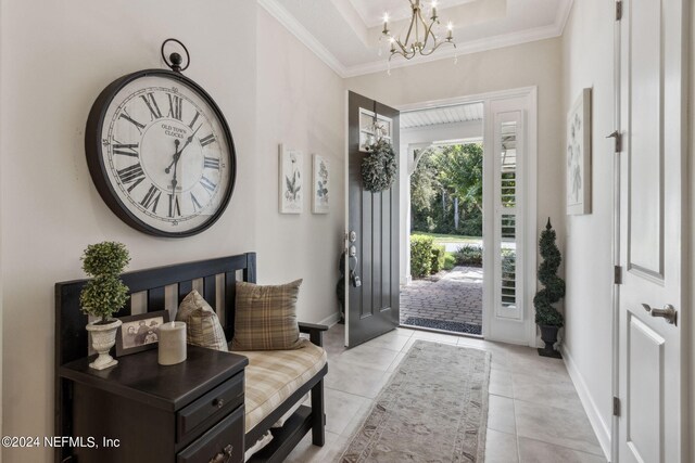 tiled foyer featuring a notable chandelier, crown molding, and a tray ceiling