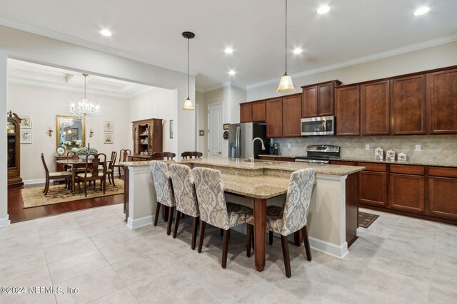 kitchen featuring light wood-type flooring, a kitchen island with sink, light stone countertops, appliances with stainless steel finishes, and ornamental molding