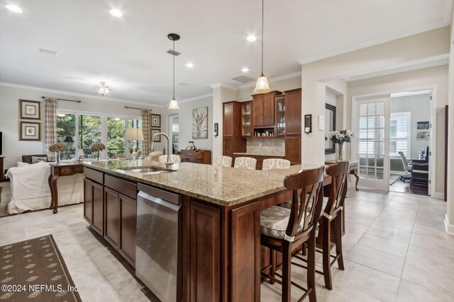 kitchen with a center island with sink, sink, decorative light fixtures, stainless steel dishwasher, and a kitchen breakfast bar