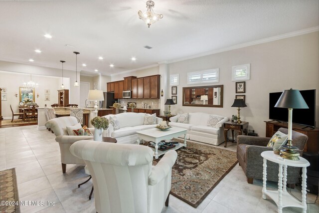 living room featuring an inviting chandelier, light tile patterned floors, and crown molding