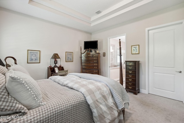 bedroom with a raised ceiling, ensuite bathroom, and carpet floors