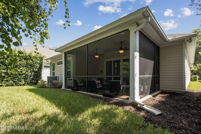 rear view of house featuring a sunroom, ceiling fan, and a lawn