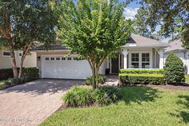 view of property hidden behind natural elements featuring a garage and a front yard