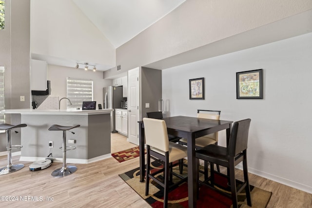 dining area featuring high vaulted ceiling and light hardwood / wood-style floors