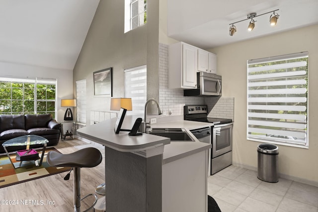 kitchen featuring sink, white cabinetry, stainless steel appliances, a kitchen bar, and kitchen peninsula