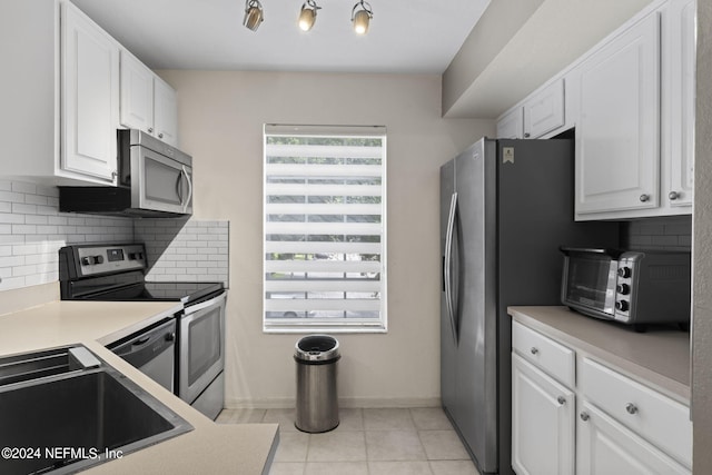 kitchen with sink, white cabinets, backsplash, light tile patterned floors, and stainless steel appliances