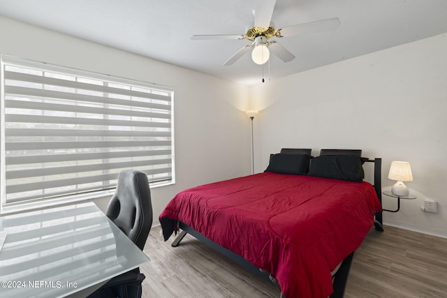 bedroom featuring ceiling fan, hardwood / wood-style floors, and multiple windows