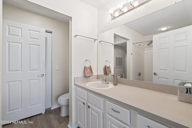 bathroom with vanity, wood-type flooring, toilet, and tiled shower