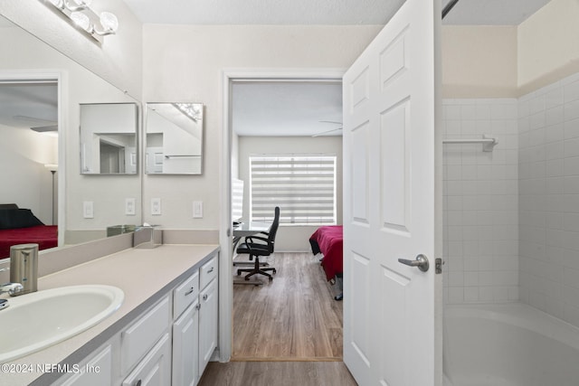 bathroom with vanity, hardwood / wood-style floors, and tiled shower / bath