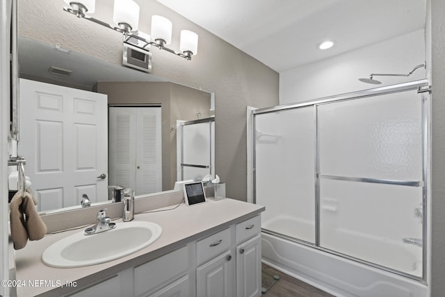 bathroom featuring hardwood / wood-style flooring, enclosed tub / shower combo, and vanity