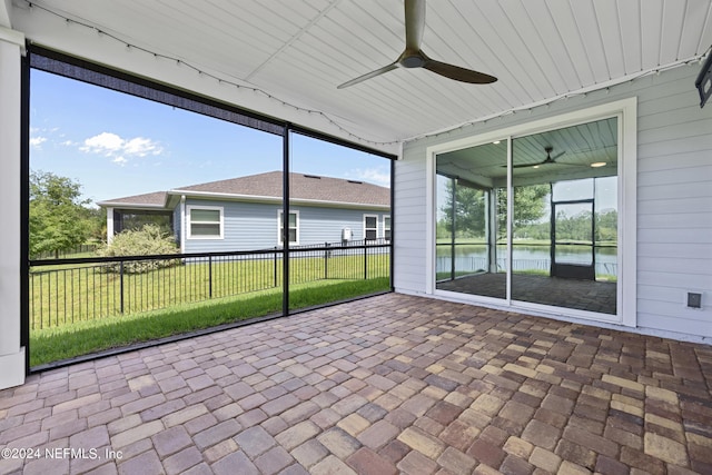 unfurnished sunroom featuring a water view, ceiling fan, and a wealth of natural light