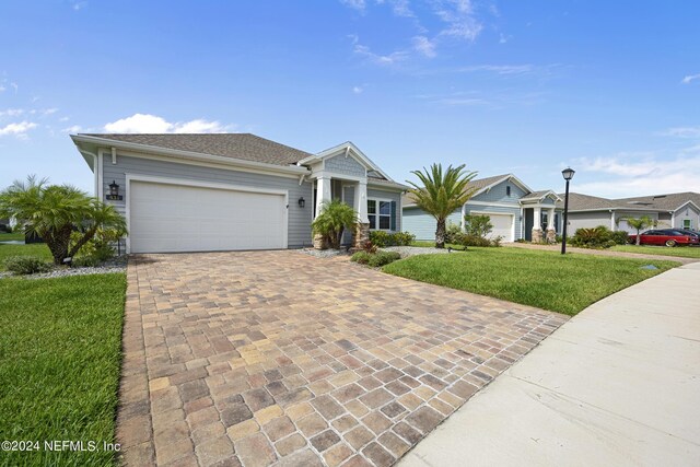 ranch-style home with a front lawn, decorative driveway, and an attached garage