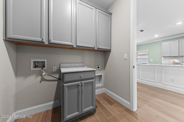 laundry room featuring cabinet space, visible vents, hookup for an electric dryer, light wood-type flooring, and washer hookup