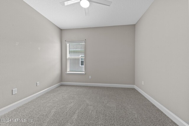 carpeted spare room featuring ceiling fan, a textured ceiling, and baseboards