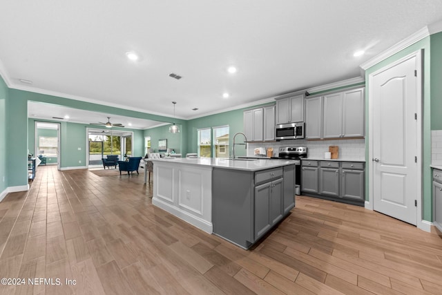 kitchen featuring gray cabinets, stainless steel appliances, a center island with sink, and a healthy amount of sunlight