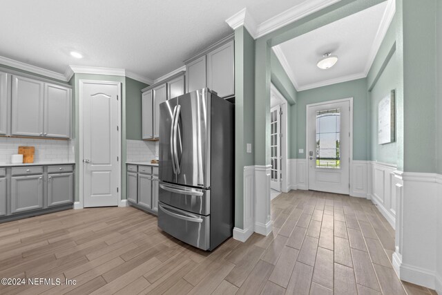 kitchen featuring light wood-style flooring, wainscoting, gray cabinets, and freestanding refrigerator