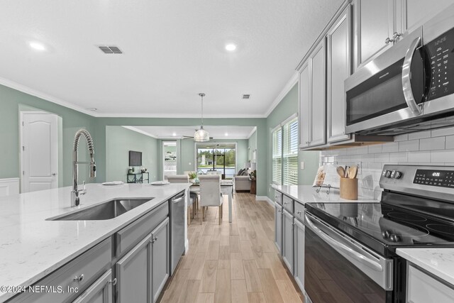 kitchen featuring visible vents, decorative backsplash, gray cabinetry, appliances with stainless steel finishes, and a sink