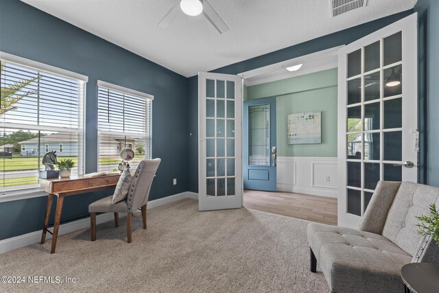 home office with ceiling fan, a wainscoted wall, carpet floors, visible vents, and french doors