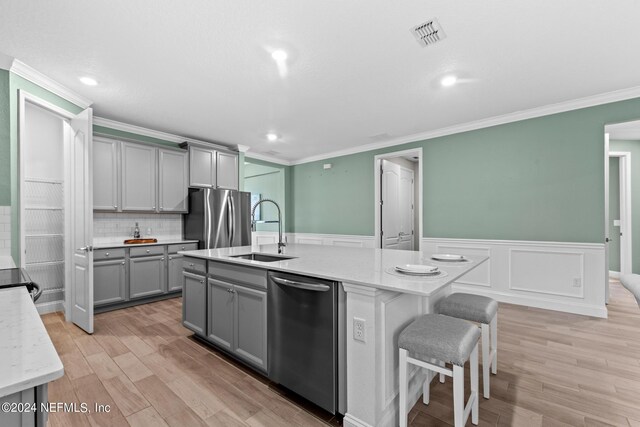 kitchen with visible vents, gray cabinetry, appliances with stainless steel finishes, a sink, and light wood-type flooring