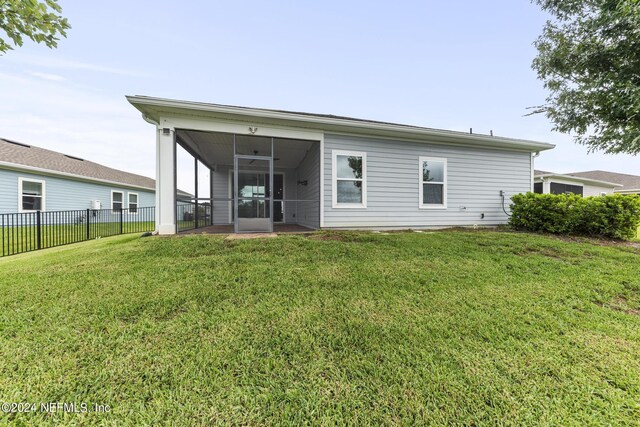 back of house with a sunroom, fence, and a lawn