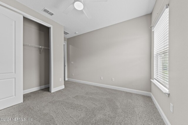 unfurnished bedroom featuring baseboards, visible vents, a ceiling fan, carpet floors, and a closet