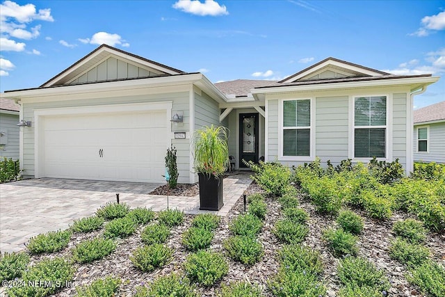 ranch-style house featuring decorative driveway, board and batten siding, and an attached garage