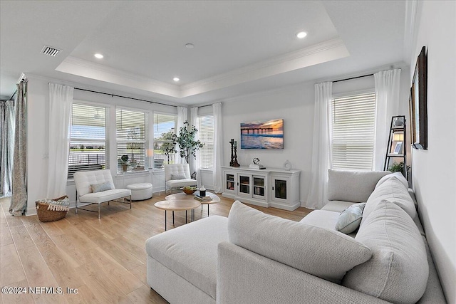 living room featuring visible vents, light wood-style flooring, ornamental molding, a tray ceiling, and recessed lighting