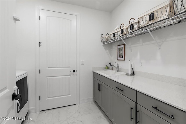 interior space with cabinet space, baseboards, washer / clothes dryer, marble finish floor, and a sink