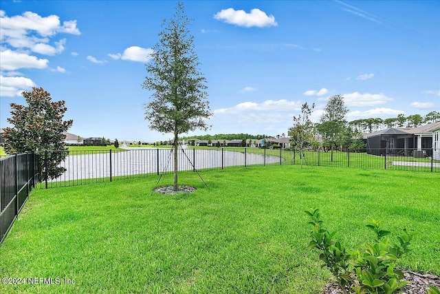 view of yard with a residential view, a fenced backyard, and a water view