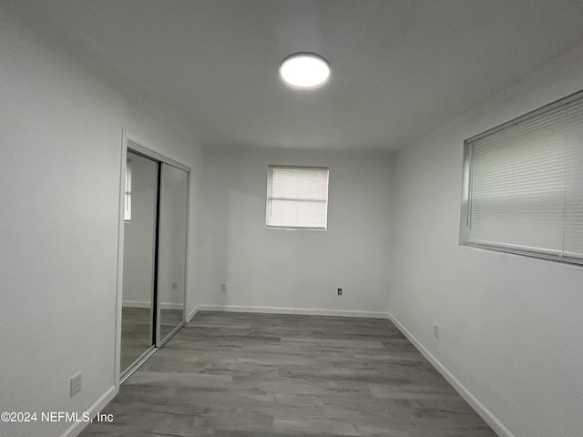 unfurnished bedroom featuring a closet, baseboards, and wood finished floors