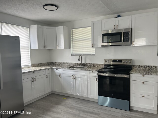 kitchen with light wood-type flooring, white cabinetry, and stainless steel appliances