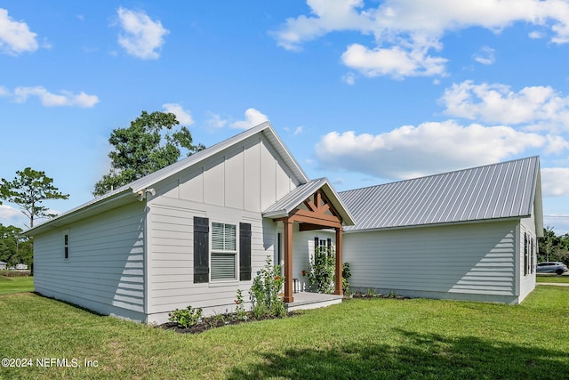 view of front of house with board and batten siding, metal roof, and a front lawn