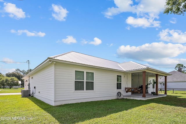 back of house with a lawn, metal roof, cooling unit, and a patio