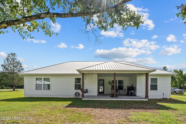 view of front of house with a front yard, a patio area, and metal roof